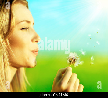 Happy woman blowing dandelion sur fond flou, s'amuser et jouer en plein air, teen girl enjoying nature Banque D'Images