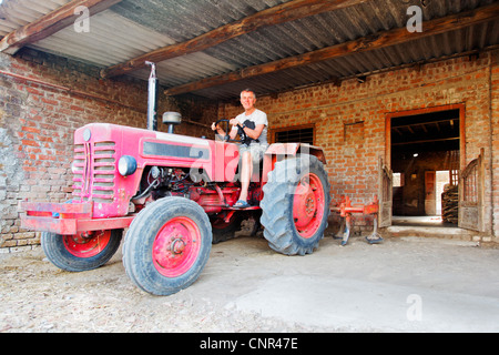 Happy farm part sur un tracteur sur le point de se déplacer hors de son rondes quotidiennes Banque D'Images