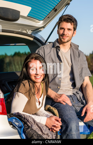 Camping young couple smiling together in car summer sunset Banque D'Images