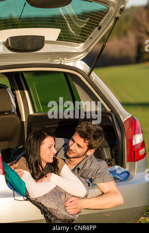 Camping jeune couple hugging ensemble dans le coucher du soleil d'été de voiture Banque D'Images