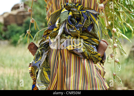 Une mère portant son enfant sur son dos tout en travaillant dans le comté de Dogon, au Mali. Banque D'Images