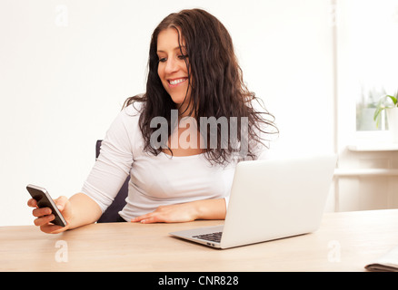 Portrait of a woman smiling while lire quelque chose sur son téléphone Banque D'Images