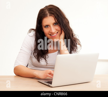 Portrait of a smiling woman en utilisant son ordinateur portable, isolé sur fond blanc Banque D'Images