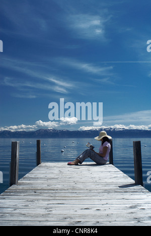 Woman sitting on wooden dock dans le lac Banque D'Images