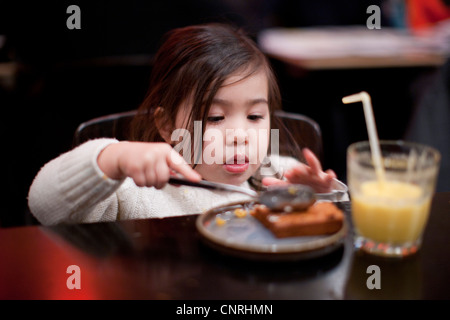 Little girl eating at table Banque D'Images