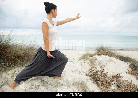 Woman practicing tai chi chuan sur plage, vue latérale Banque D'Images