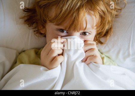 Boy covering face avec feuille, portrait Banque D'Images