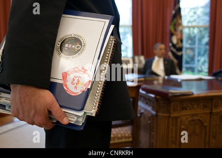 Le président Barack Obama est présenté par Denis McDonough, sous-conseiller pour la sécurité nationale et d'autres dans le bureau ovale le 29 mars 2012 à Washington, DC. Banque D'Images