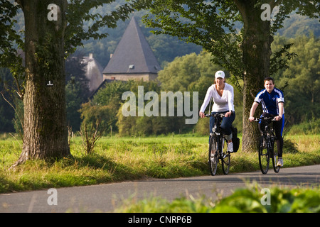 Jeune couple à vélo sur la piste cyclable de la vallée de la Ruhr Kemnade, château en arrière-plan, l'Allemagne, en Rhénanie du Nord-Westphalie, Ruhr, Witten Banque D'Images