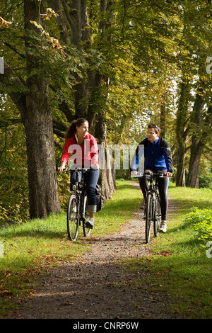 Jeune couple sur des vélos sur la piste cyclable de la vallée de la Ruhr à l'avenue près de château, Allemagne, Kemnade-du-Nord-Westphalie, Ruhr, Hattingen Banque D'Images