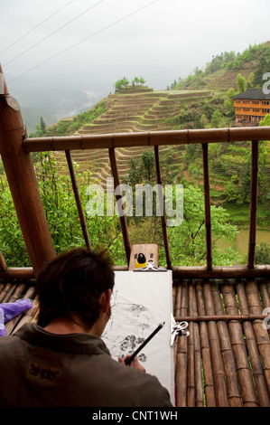 Un peintre à la recherche d'inspiration parmi les rizières en terrasses, Da Zhai Village, Province du Guangxi, Chine Banque D'Images