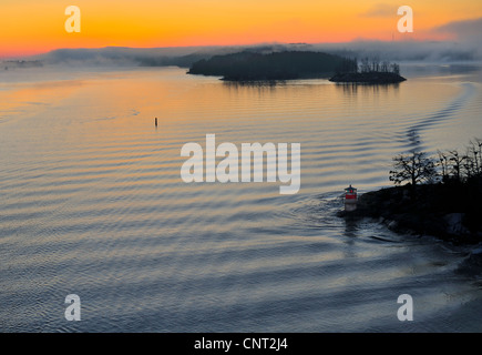 Ryssmasterna Lighthouse (ARY) et spectaculaire lever du soleil orange avec les îles de l'archipel de Stockholm, Suède, en silhouette haute grand angle presque vue aérienne du sommet d'un grand bateau de croisière. Banque D'Images