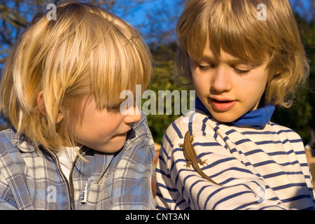 Lézard vivipare, lézard commun européen (Lacerta vivipara, Zootoca vivipara), deux enfants avec un lézard sur l'épaule de l'un d'entre eux, Allemagne Banque D'Images