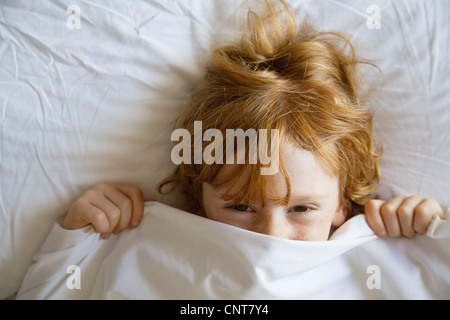 Boy covering face avec drap de lit, juste au-dessus Banque D'Images