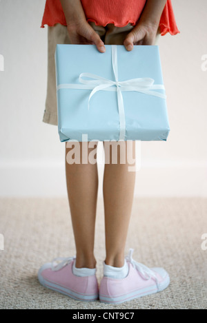 Girl holding gift derrière le dos, low section Banque D'Images