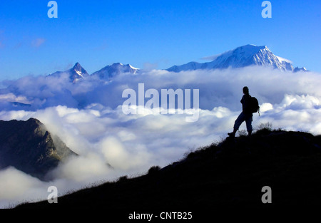 Silhouette d'un randonneur en face du Massif du Mont-Blanc briser une couverture nuageuse, France, Alpes Banque D'Images