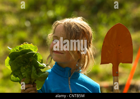 8 ans girl gardening avec godet et salade verte dans ses mains, France Banque D'Images