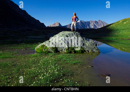Jeune femme debout sur un rocher à un lac de montagne, en France, du Parc National de la Vanoise Banque D'Images