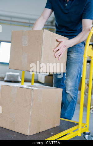 L'empilement des boîtes de carton Man sur dolly Banque D'Images