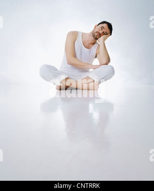 Cross-legged man resting head in hands Banque D'Images