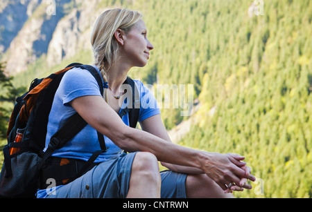 Une femme assise à la recherche jusqu'au randonneur d'une montagne, si peu de Trail, Washington, USA. Banque D'Images