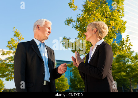 Les gens d'affaires - et bien - debout dans un parc en plein air de parler Banque D'Images
