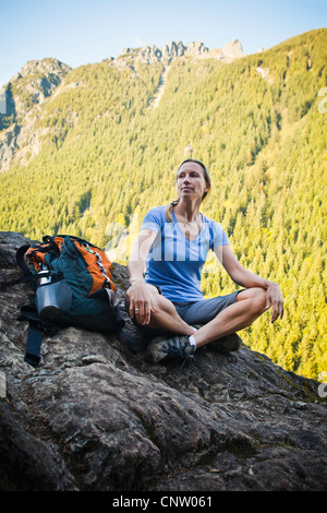 Randonneur une femme assise sur le bord d'une falaise rocheuse, si peu de Trail, Washington, USA. Banque D'Images