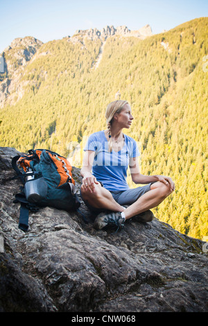 Randonneur une femme assise sur le bord d'une falaise rocheuse, si peu de Trail, Washington, USA. Banque D'Images