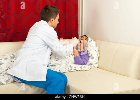 Femme médecin patient examiner pour mal de gorge dans son canapé home Banque D'Images