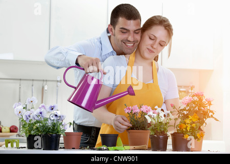 Couple d'arroser les plantes en pots à l'intérieur Banque D'Images