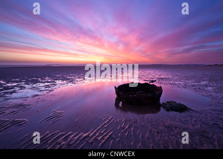 Un vieux Rusty Bucket se situe dans un bassin d'eau au lever du soleil sur la plage de Thornham à Norfolk, UK Banque D'Images