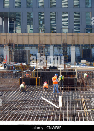 Groupe de bar benders fixant l'armature en acier au grand site en construction Banque D'Images