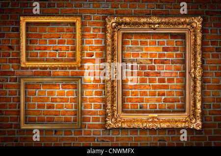 Cadres dorés ornés d'accroché sur un mur de briques. Banque D'Images