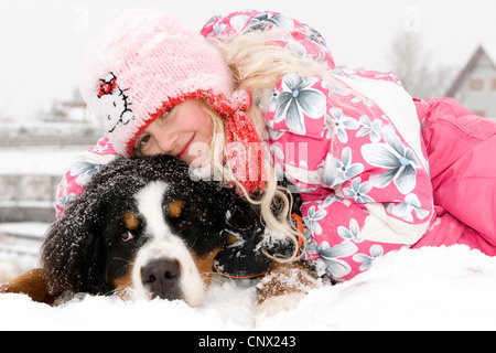 Bernois (Canis lupus f. familiaris), girl avec son chien dans la neige Banque D'Images