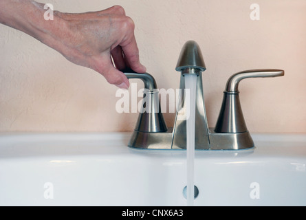Close up of hand tournant sur évier robinet, l'eau courante. Banque D'Images