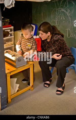 Avec l'aide d'un membre du personnel formé un garçon aveugle sur une machine à écrire braille types à l'intention des enfants aveugles Centre d'apprentissage. Banque D'Images