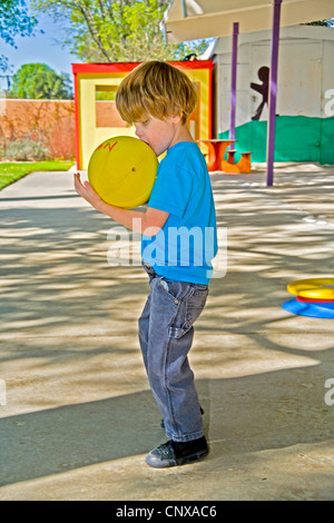 Un garçon aveugle en étreignant un 'chant' spécial ballon de soccer au centre d'apprentissage pour enfants aveugles à Santa Ana, CA. Banque D'Images