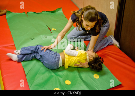 Enseignant encourage une vision réduite girl lors d'un jeu de piste dans un groupe moteur sensoriel des enfants aveugles au centre d'apprentissage. Banque D'Images