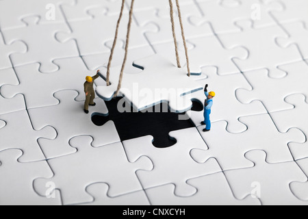 Ouvriers miniature une pendaison directeurs en place de pièce de puzzle Banque D'Images