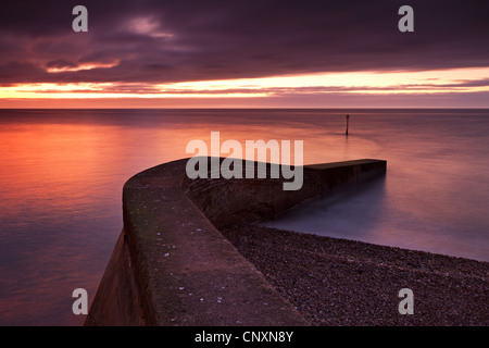 Jetée de pierre sur la plage au lever du soleil, Sidmouth, Cornwall, Devon, Angleterre. L'hiver (Janvier) 2012. Banque D'Images