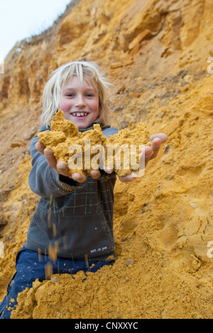 Garçon la collecte des sols colorés afin de mélanger la peinture avec elle avec l'eau et collez, Allemagne Banque D'Images