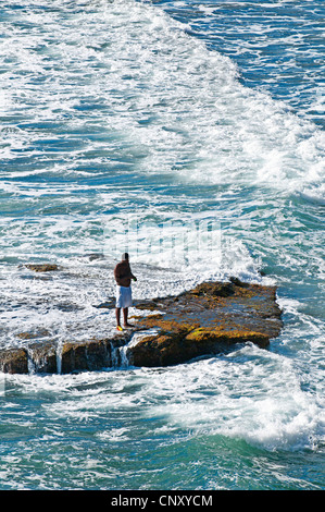 Pêcheur debout sur un rocher dans le surf, Saint Vincent et les Grenadines, Biabou Bay Banque D'Images