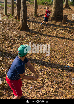 Deux jeunes garçons cubains jouent un jeu de 'stick ball' parmi les arbres de la petite ville de Viñales, Cuba. Banque D'Images