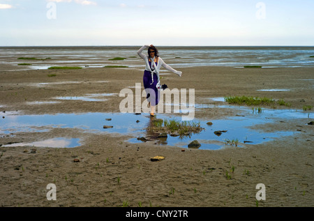 Young woman walking barfoot à travers la mer des Wadden, ALLEMAGNE, Basse-Saxe Banque D'Images