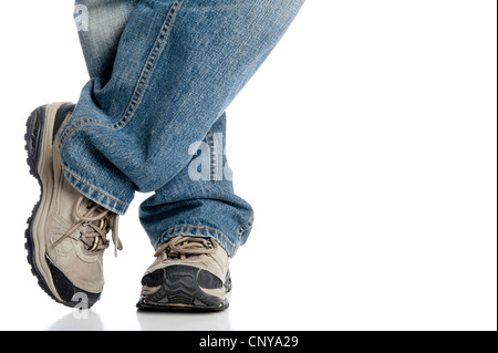 Close-up of man's pieds et chaussures de sport tout en se tenant nonchalamment croisés avec un pied devant l'autre, isolé sur blanc Banque D'Images