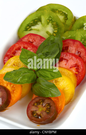 Différentes variétés de tomates biologiques tranches sur une assiette, in front of white background Banque D'Images