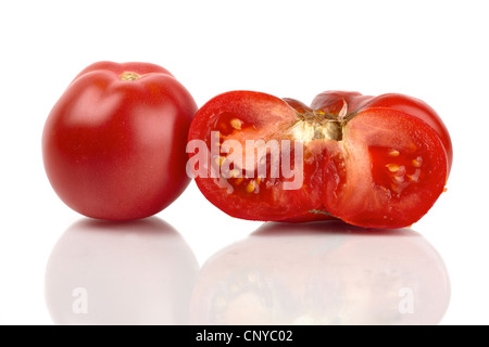 Deux grosses tomates biologiques, l'un ensemble et une moitié reflétait in front of white background Banque D'Images