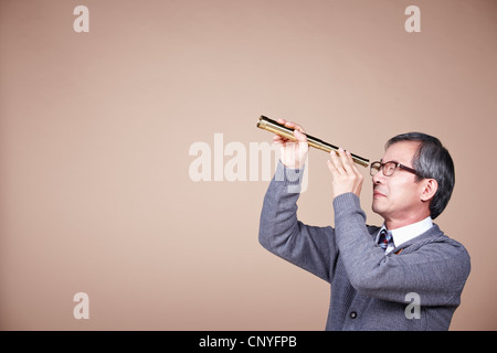 Un vieil homme looking through telescope Banque D'Images
