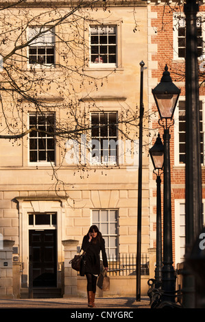 Une jeune femme marche et parle sur son téléphone portable, Queen Square, dans la vieille ville de Bristol, Royaume-Uni Banque D'Images