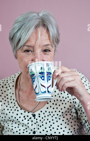 Femme d'âge moyen de boire le thé de Rennie Mackintosh mug Banque D'Images